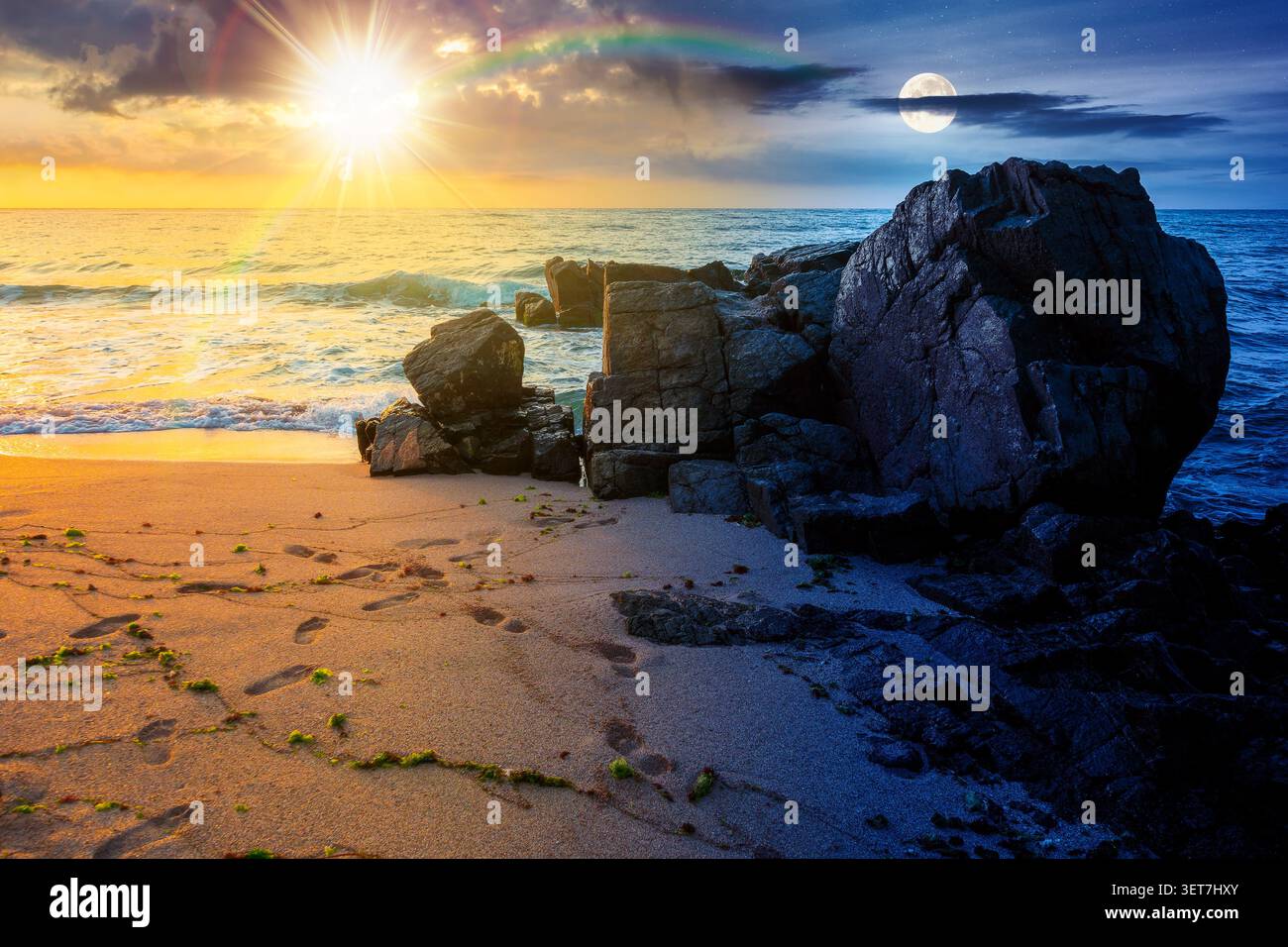 huge stones on the sandy beach. day meet night. wonderful holiday season background at the sea at twilight. sun and moon over clouds on the epic sky a Stock Photo