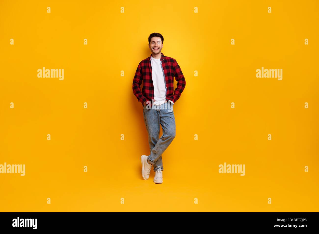 Smiling Young Caucasian Man Posing With Hands In Pockets On Yellow Background Stock Photo