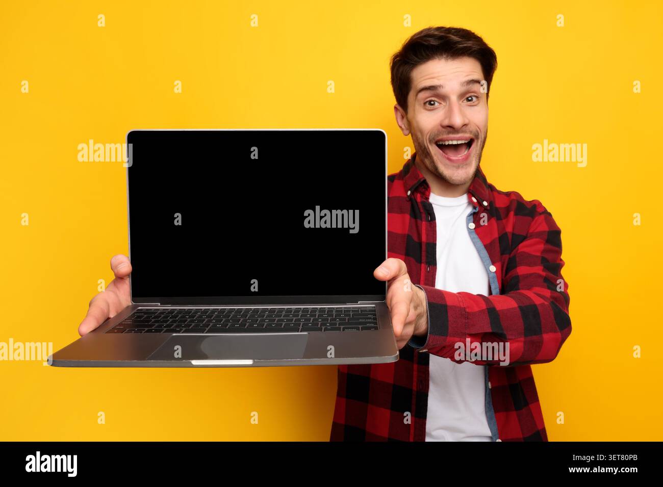 Happy Male Holding Laptop With Blank Screen, Smiling In Studio, Technology Concept Stock Photo