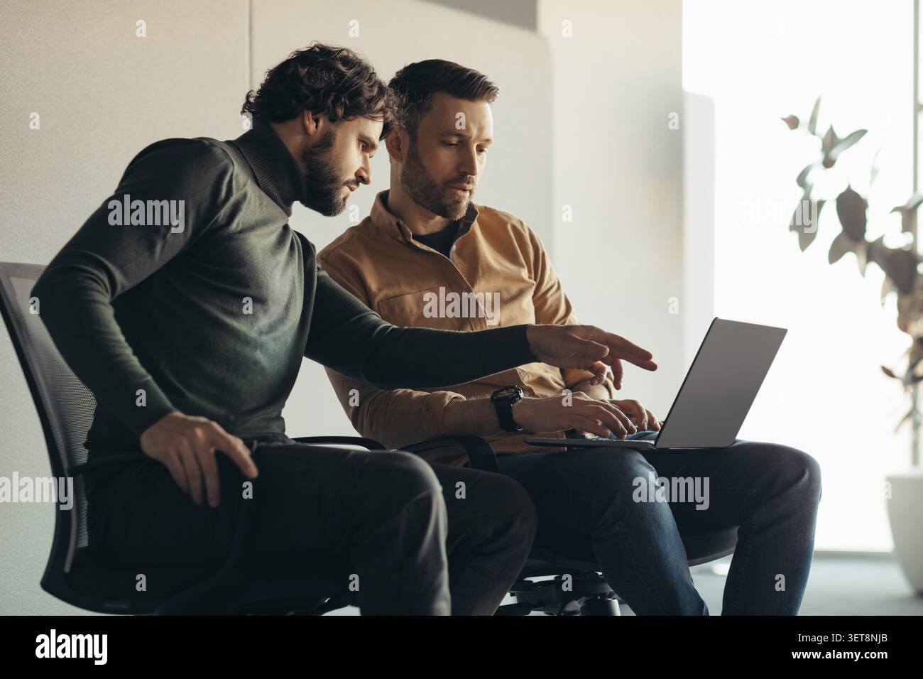 Two Men Collaborating At Desk In Modern Office, Business Concept Stock Photo