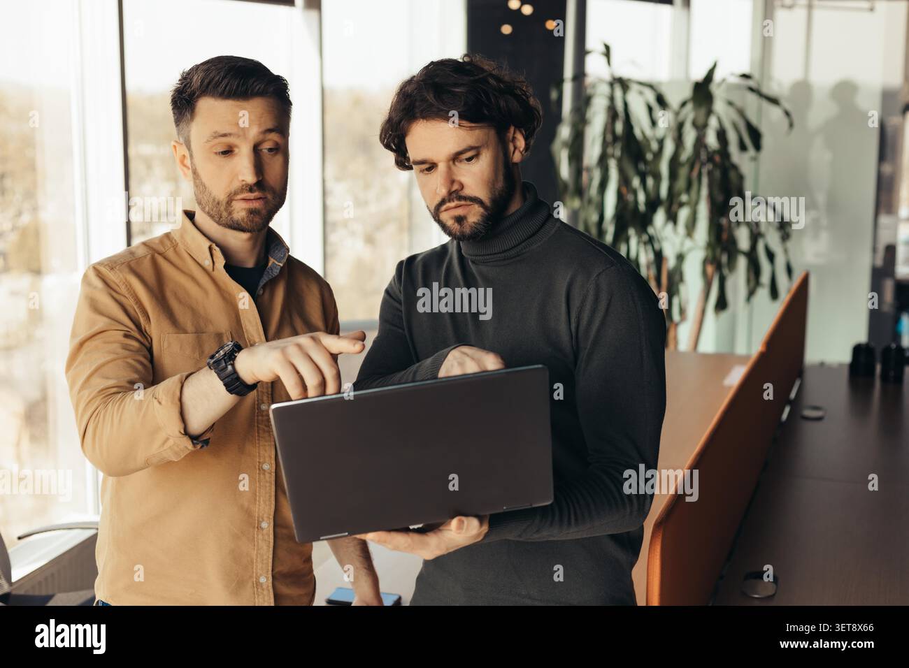 Two Men Analyzing Data On Laptop In Office, Business Concept Stock Photo