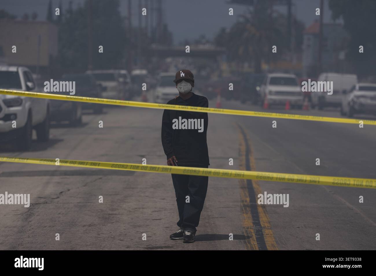 A person wears a mask while watching firefighters fight a warehouse ...