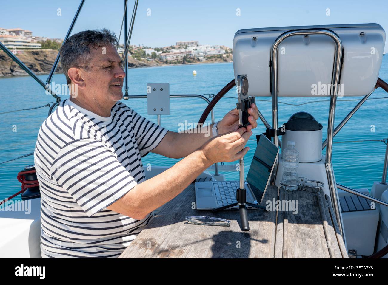 Man working remotely on sailboat setting up smartphone Stock Photo