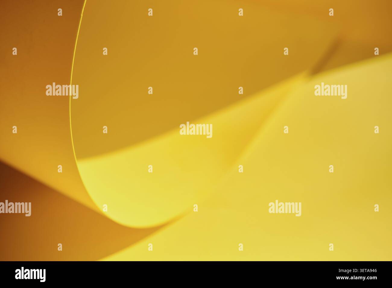 Yellow paper forms abstract curves and dynamic waves with shadows Stock Photo