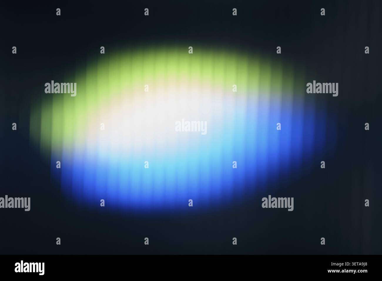 Abstract glowing light that creates a glowing green, white and blue gradient pattern on a dark background Stock Photo