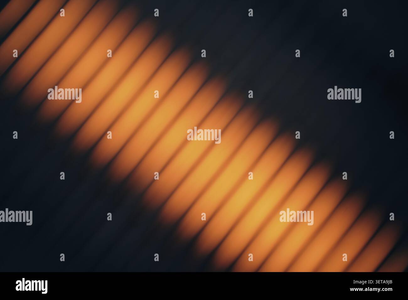Orange light that creates a blurry diagonal line pattern on a dark background Stock Photo