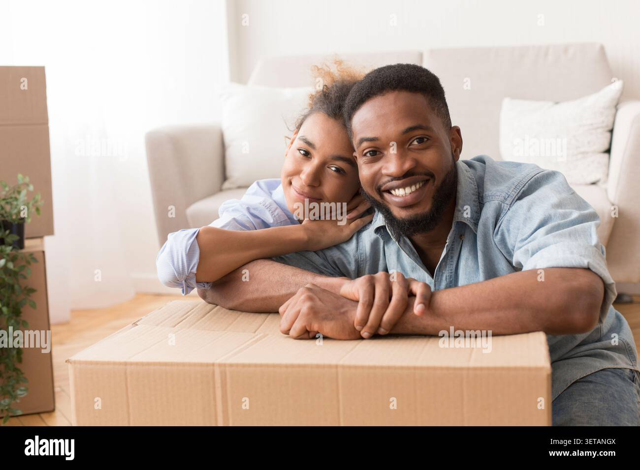 Afro Spouses Embracing Among Unpacked Moving Boxes In New Flat Stock Photo