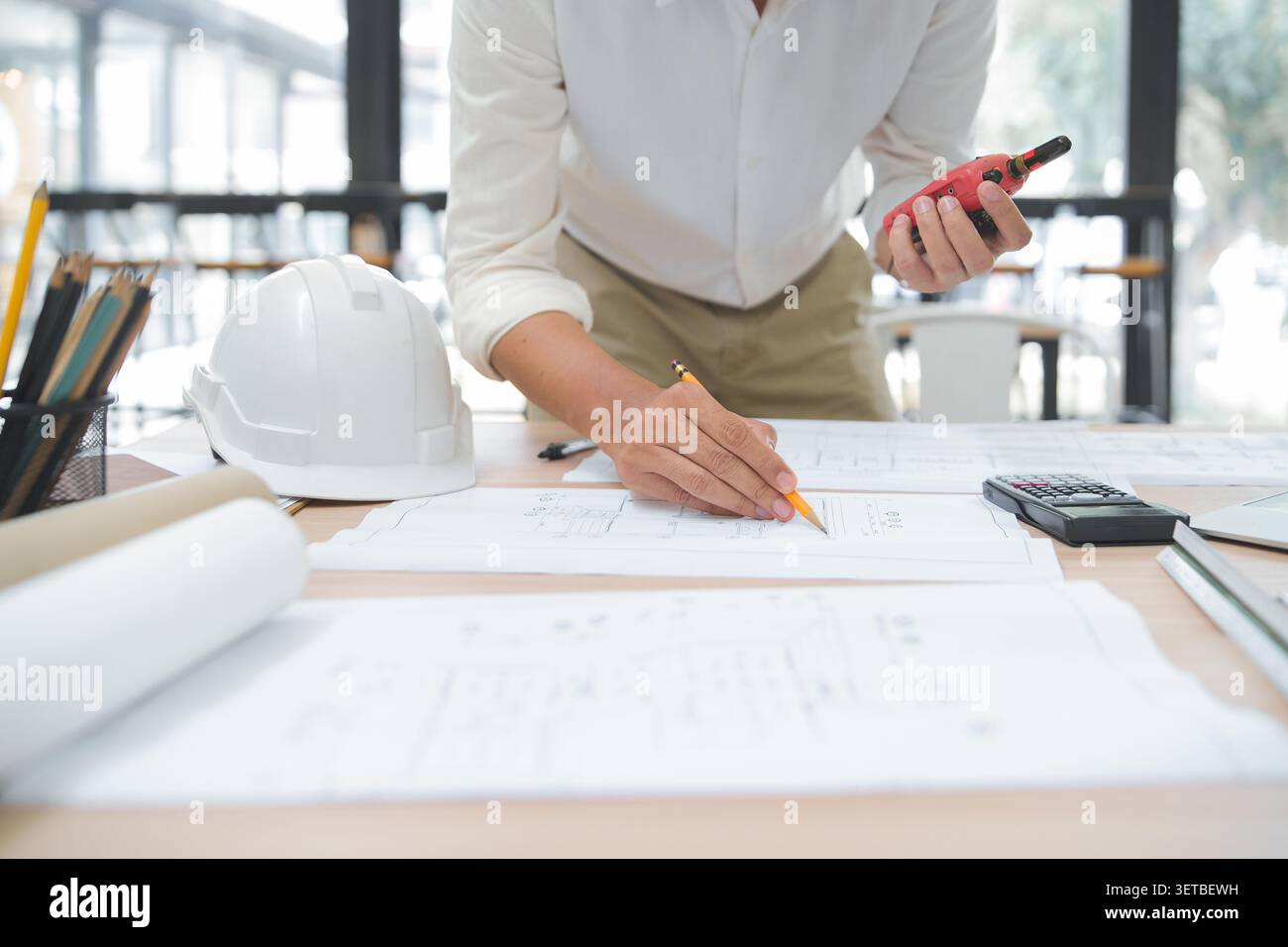 Engineer Reviewing Construction Plans with Tools in Office Envir Stock Photo