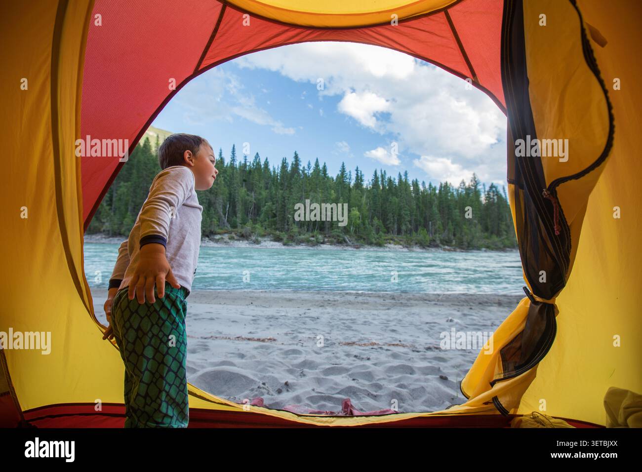 Curious boy camping by a river in the forest Stock Photo