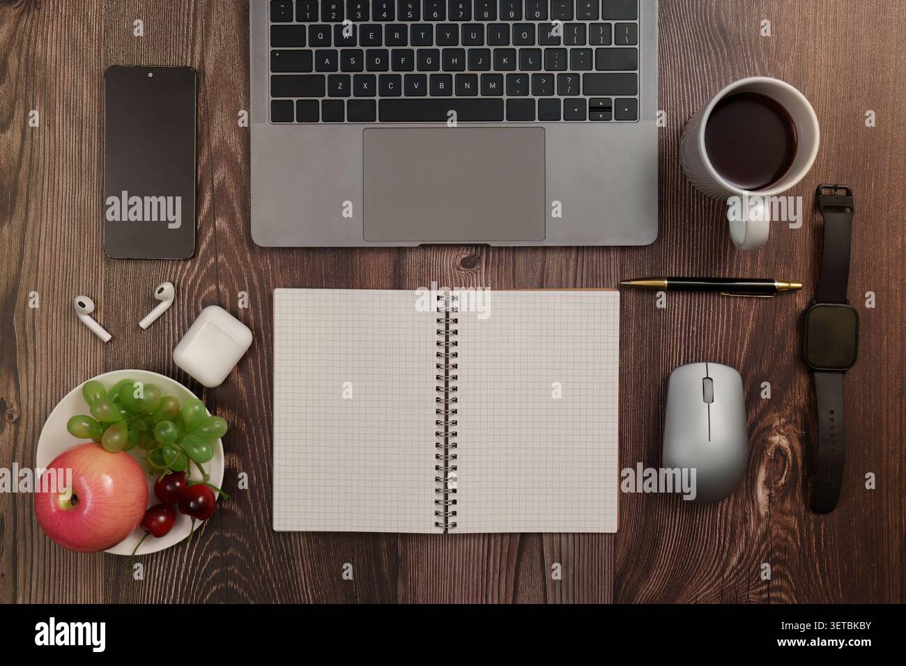 Flat lay of laptop notebook and healthy fruit snack on wooden desk for remote work productivity Stock Photo