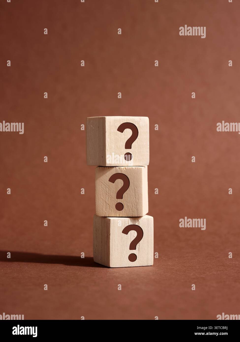 Stack of three wooden cubes with question marks on brown background representing frequently asked questions, problem solving and business solution Stock Photo