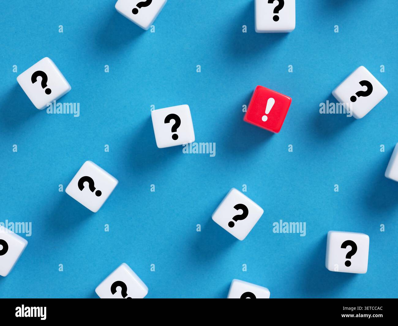 Red exclamation mark cube standing out among white question mark cubes, symbolizing finding a solution or answer to a problem Stock Photo