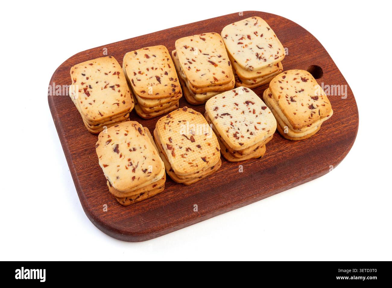 A heap of rectangular cranberry butter cookies with dried fruit bits scattered on a white background. Stock Photo