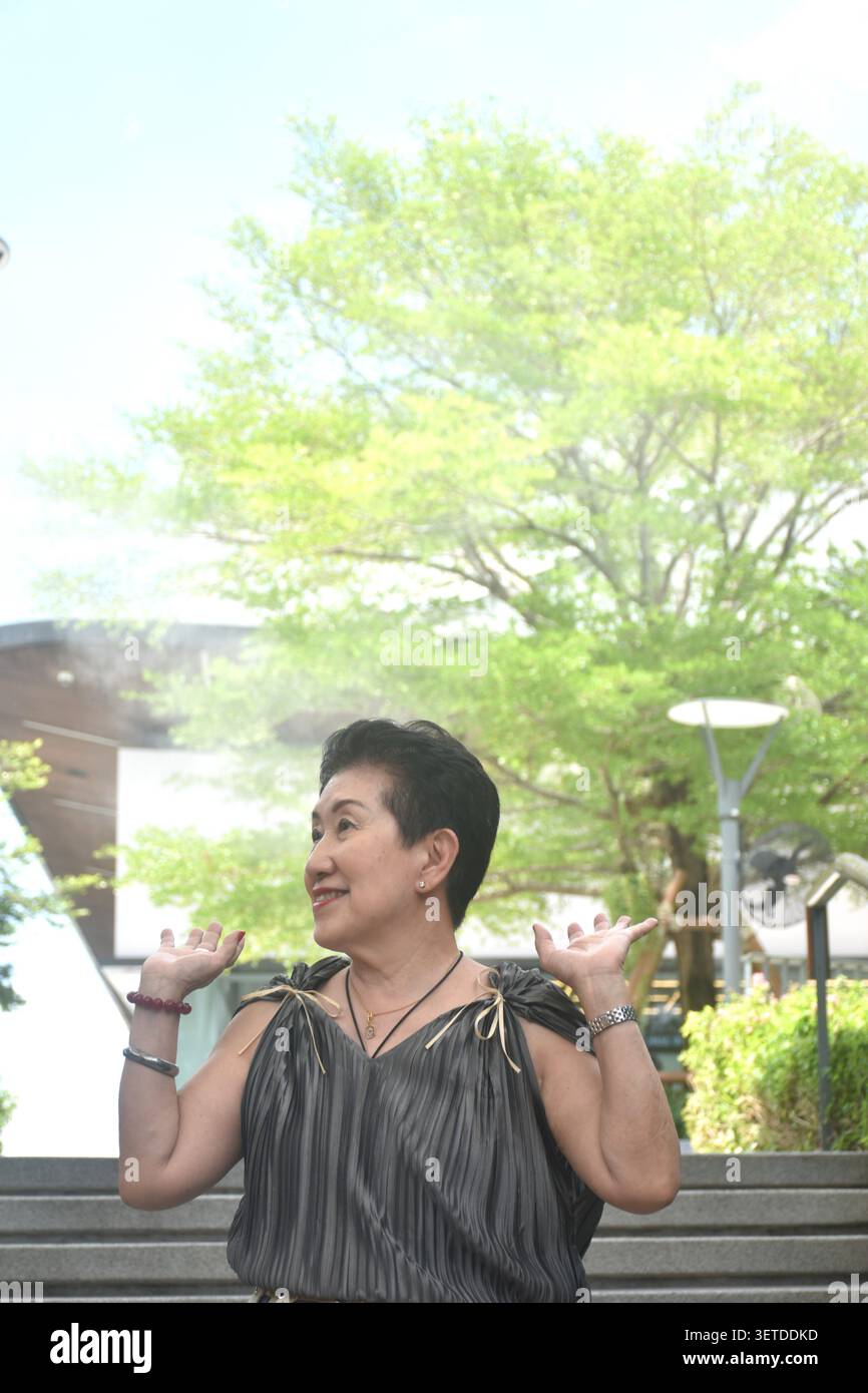 elder woman strong and healthy posing and smiling in community mall garden Stock Photo
