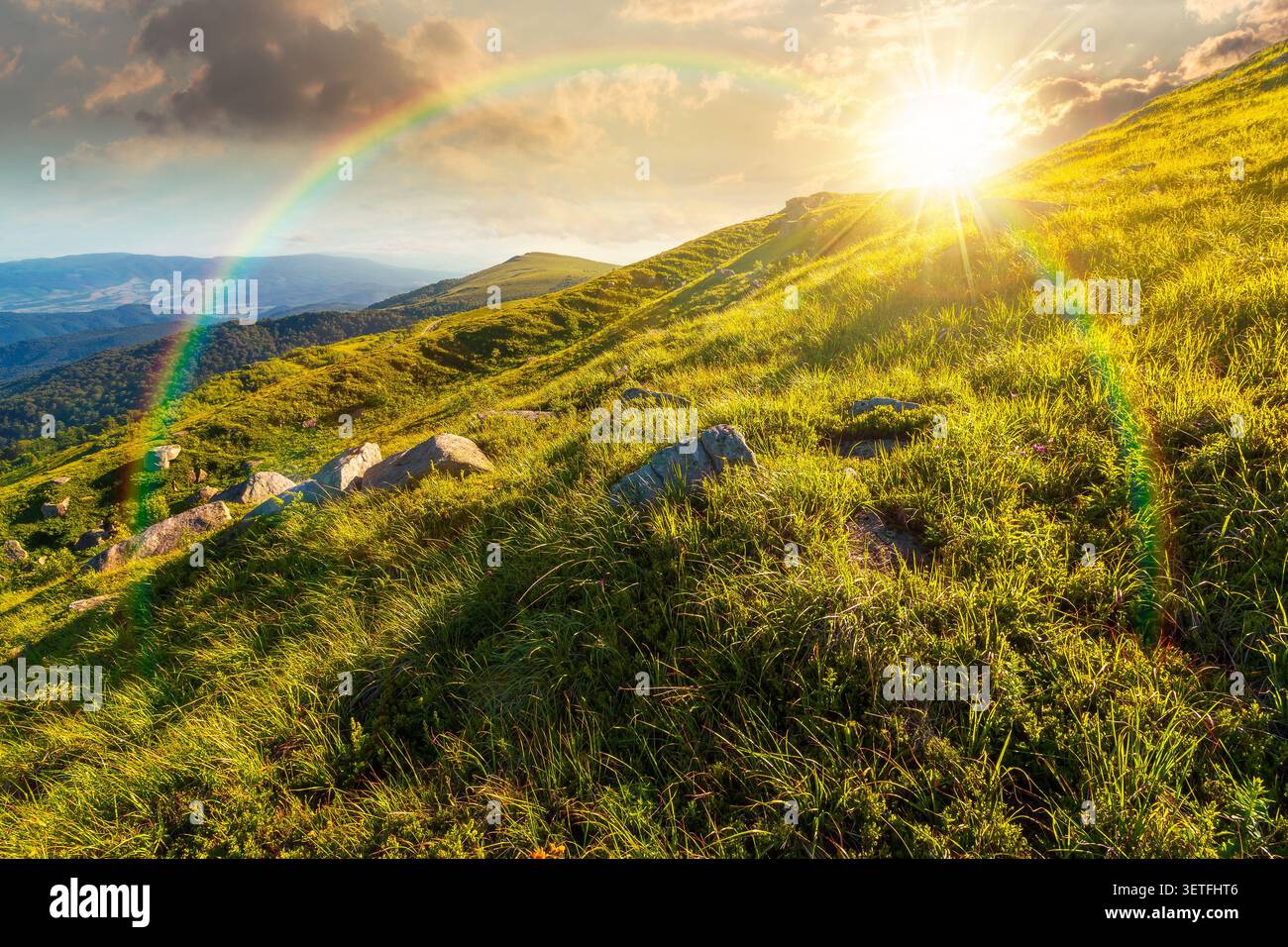 sunset over mountain landscape with grass and rock on a slope. view in to the distant valley of carpathian mountains. mountainous scenery of ukraine i Stock Photo
