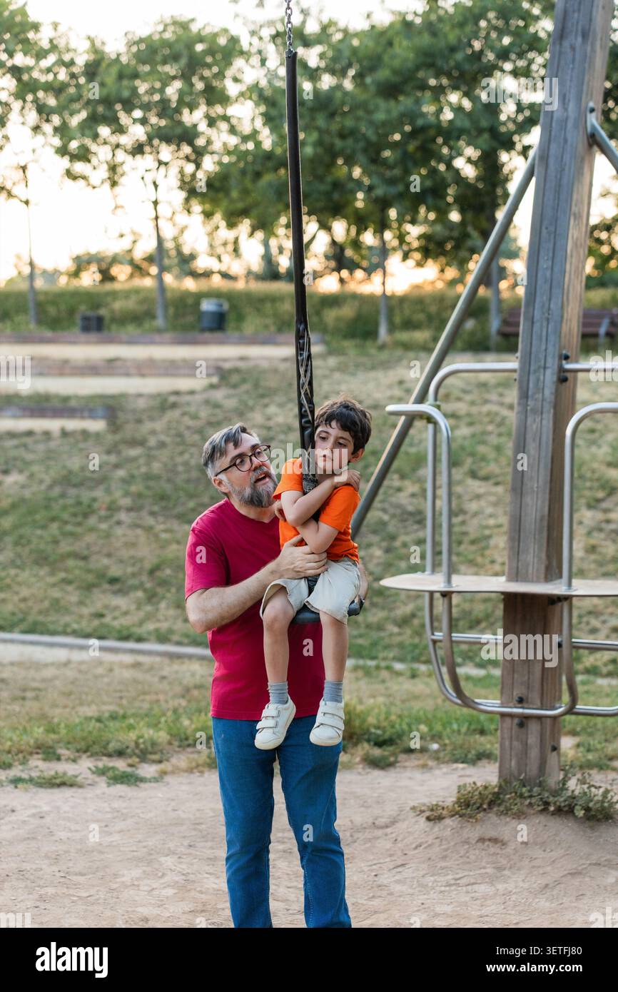 Father supporting son overcoming challenge on zipline Stock Photo