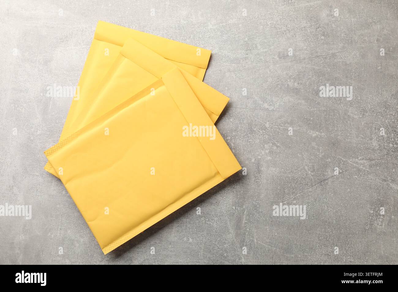Stack of yellow envelopes on grey table, top view. Space for text Stock Photo