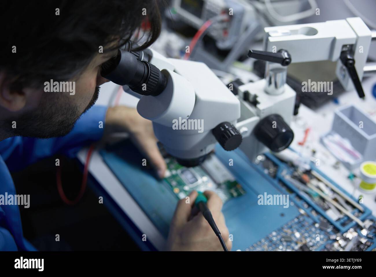 Technician repairing circuit board under microscope Stock Photo