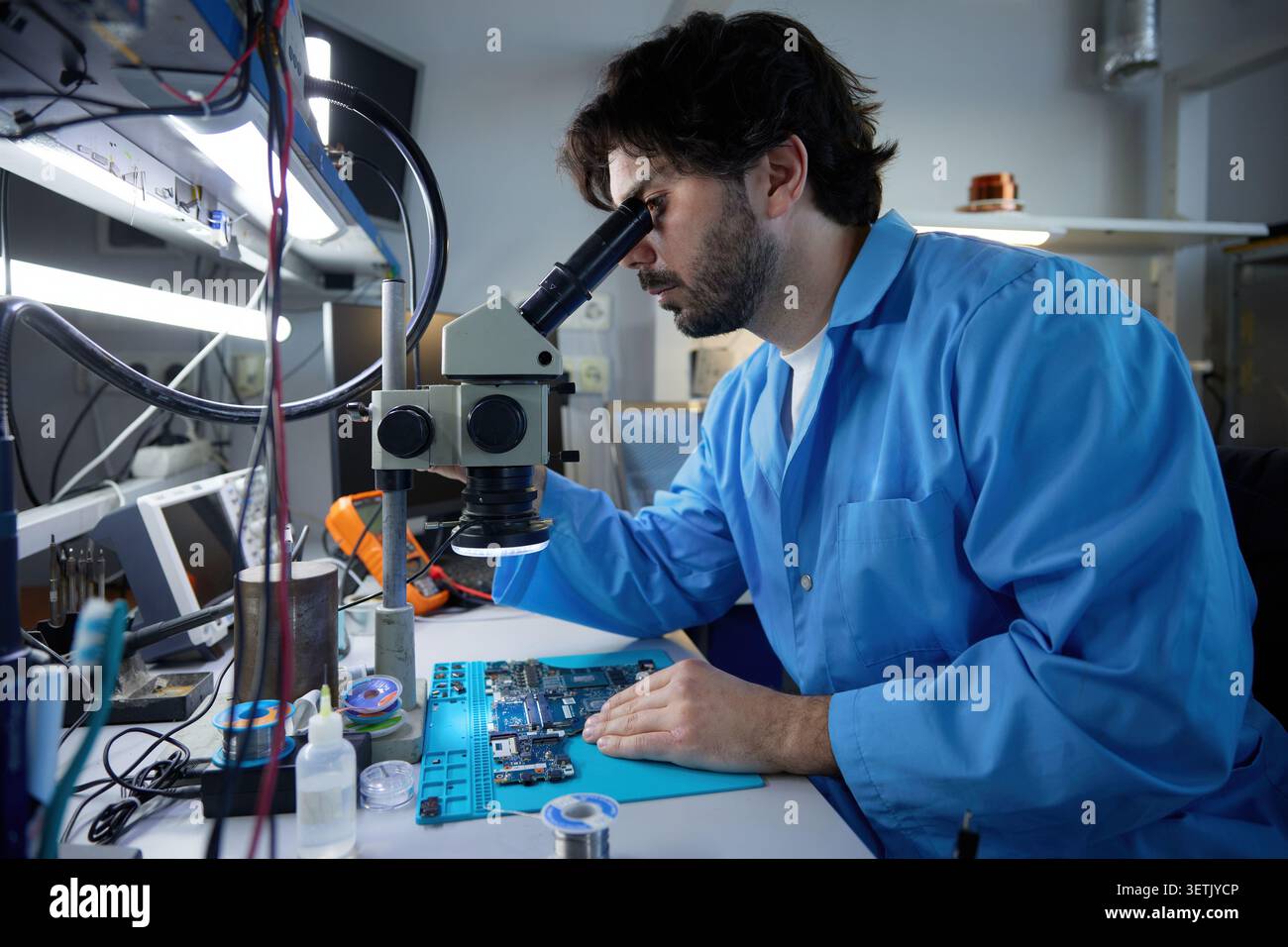 A technician repairing circuit board under microscope Stock Photo