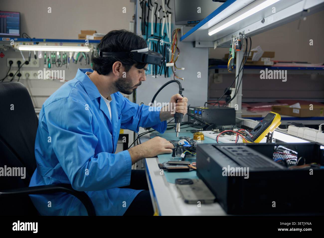 A man soldering technician is fully focused on working on a computer Stock Photo