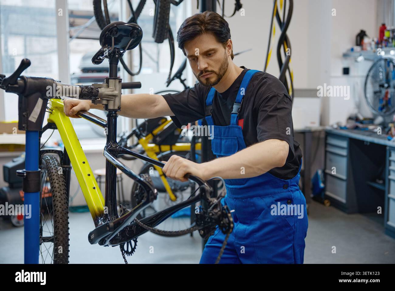 Skilled worker calibrating bicycle brake cable in workshop Stock Photo