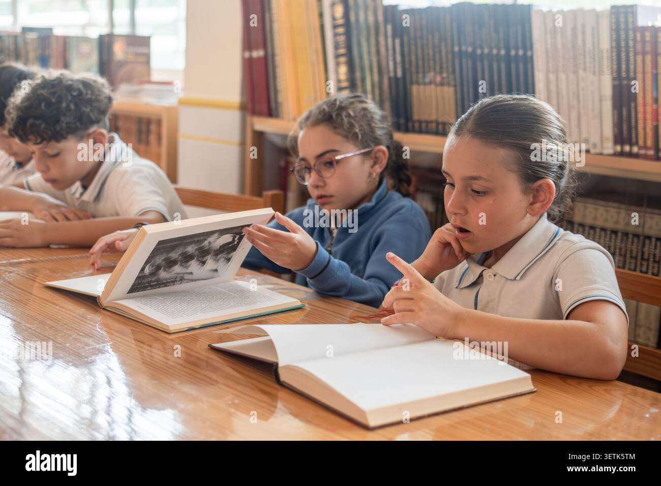 Elementary School Students Reading Books Together in Library Stock Photo