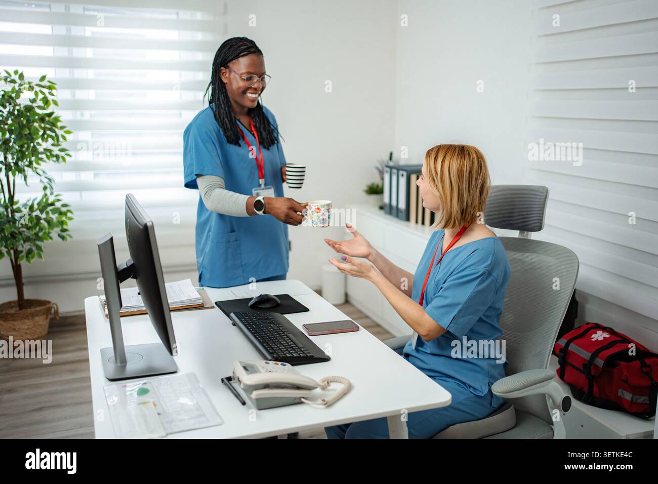 Diverse healthcare workers enjoying a coffee break in a modern hospital setting Stock Photo