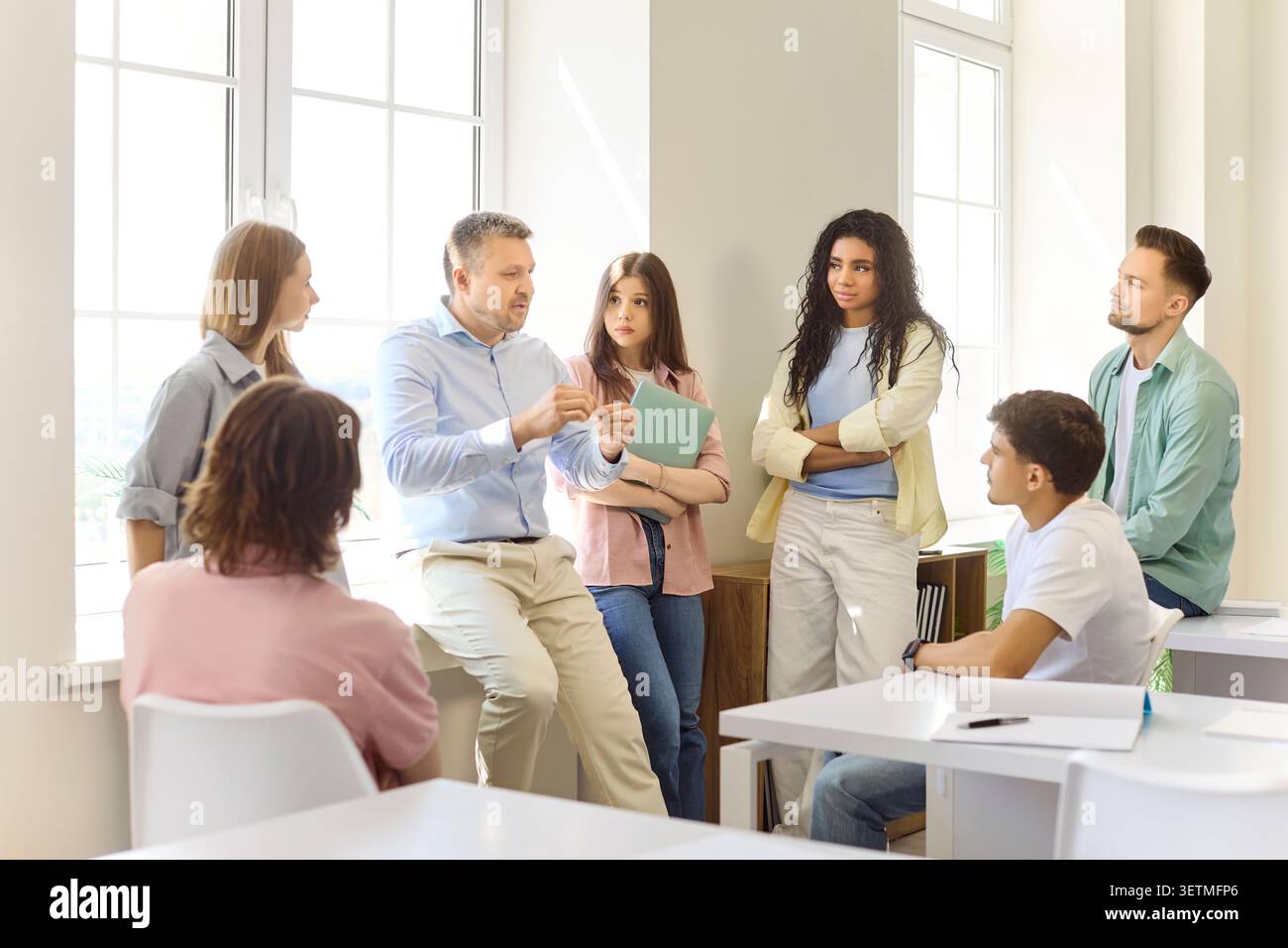 Professor explaining to diverse students during group discussion in classroom Stock Photo