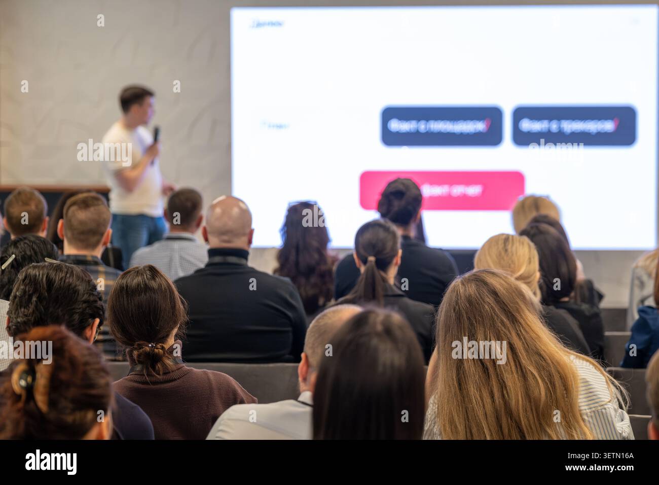 Group of professionals listening to speaker during business presentation, collaborative learning, networking atmosphere. Stock Photo