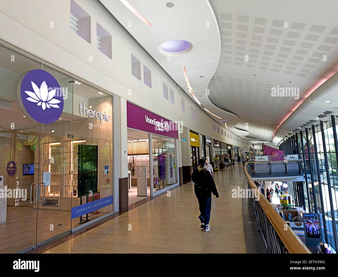 A shopper passes fashion and beauty stores on the upper mall of Dundee’s modern Overgate retail centre Stock Photo