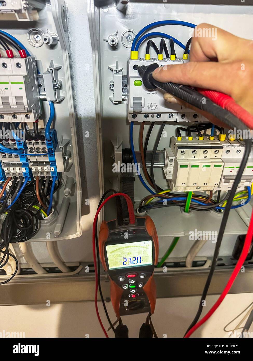 Measuring voltage with multimeter in electrical panel Stock Photo