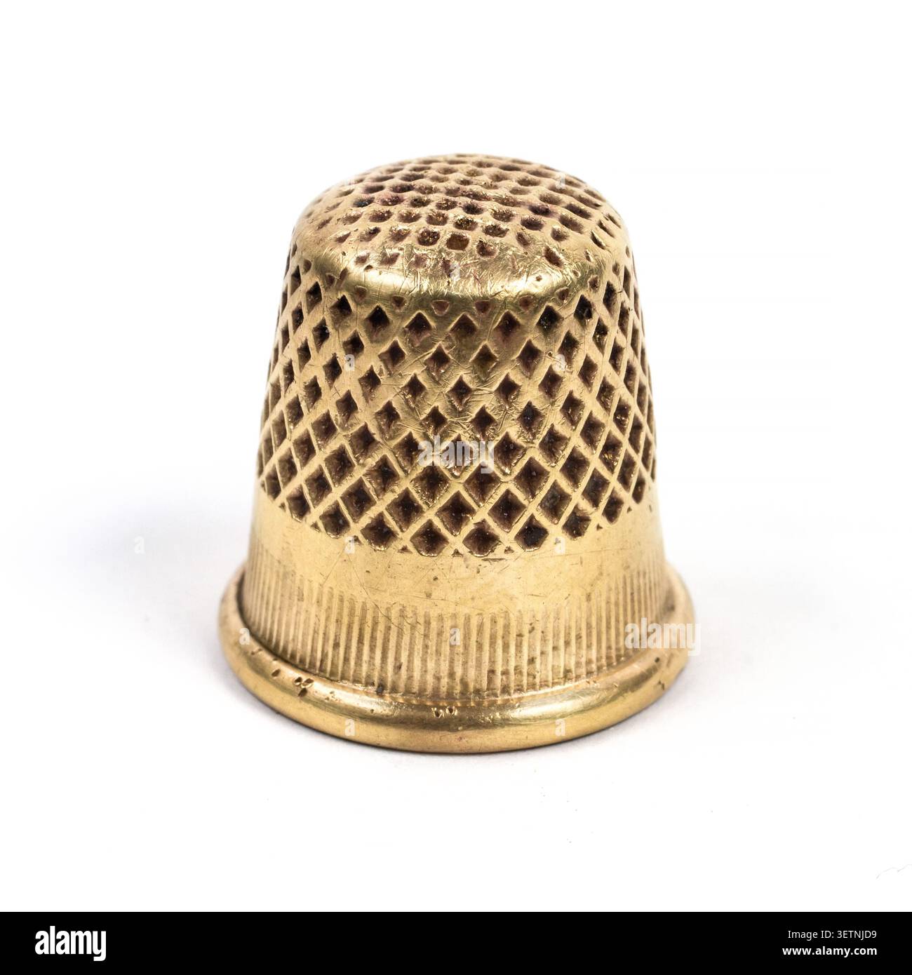 Metal thimble for sewing. Antique copper thimble on a white background. Stock Photo