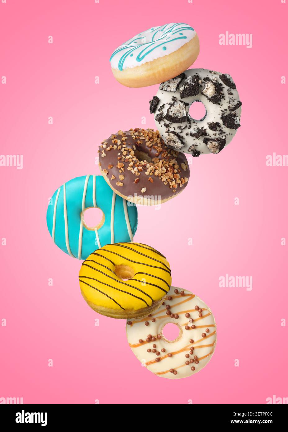 Yummy donuts covered with icing falling on pink background Stock Photo