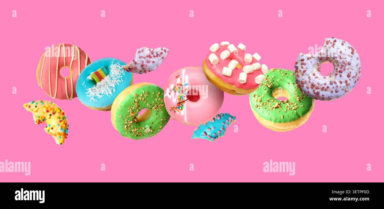 Tasty donuts covered with icing falling on pink background Stock Photo