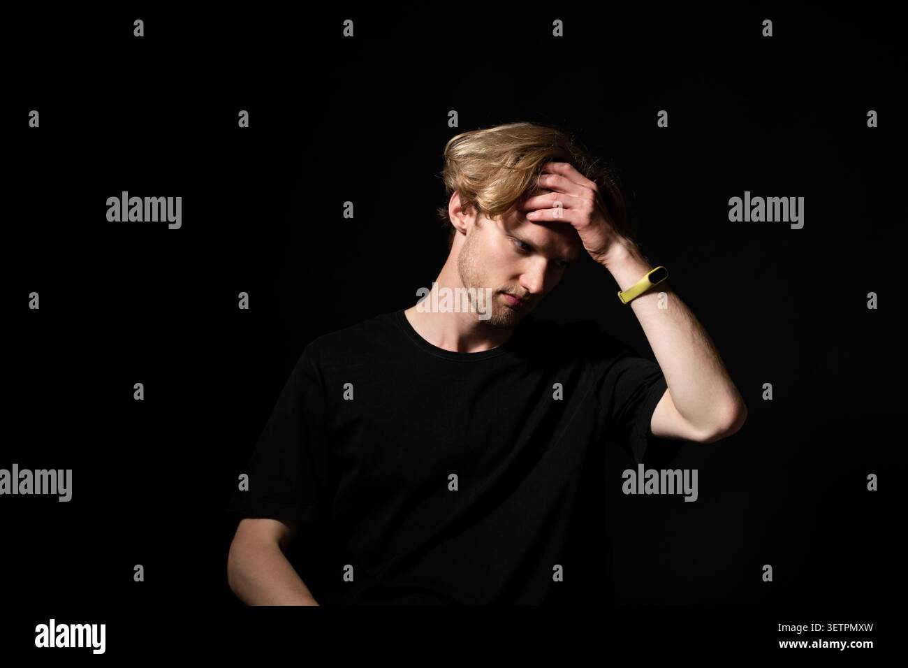 Young man feeling stressed and overwhelmed, suffering from headache or mental fatigue while contemplating a problem or difficult decision, isolated Stock Photo