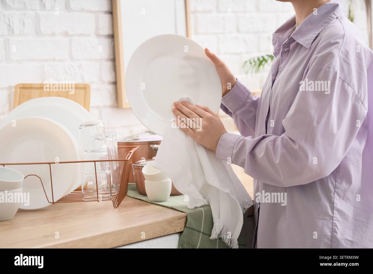 Person drying clean dishes in kitchen Stock Photo