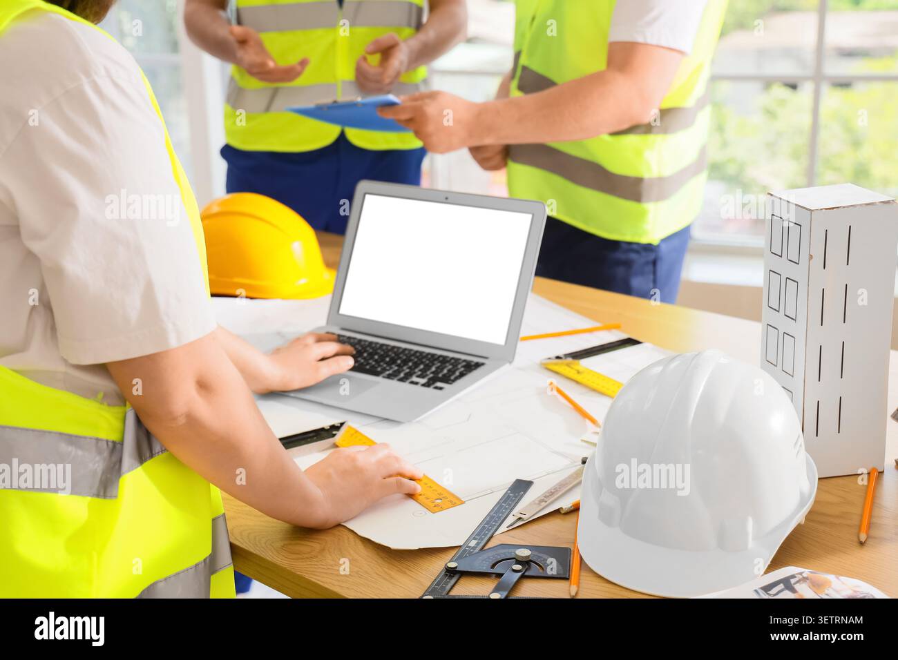Engineers collaborating on construction project with laptop and blueprints Stock Photo
