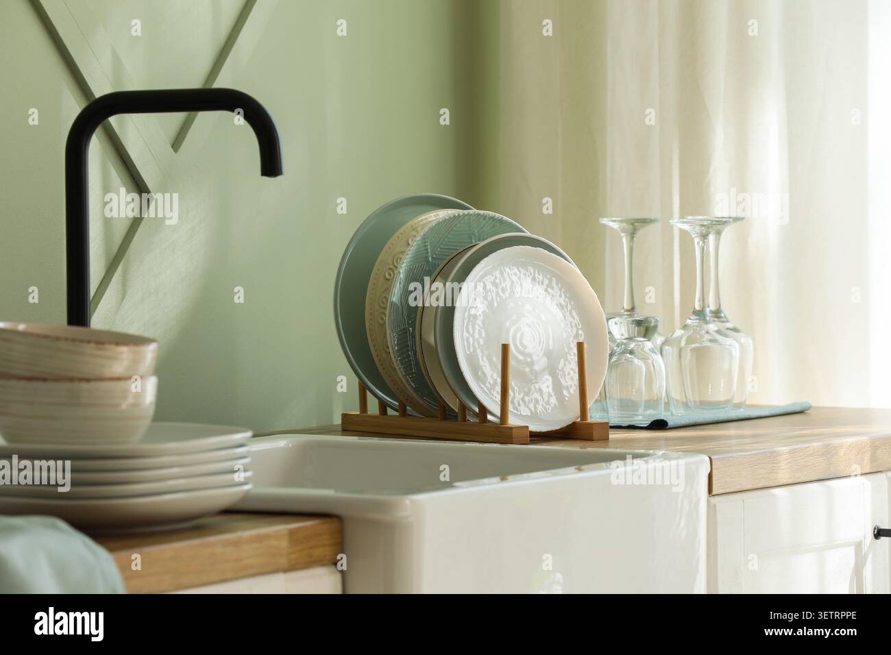 Clean dishes drying on rack in kitchen sink area Stock Photo