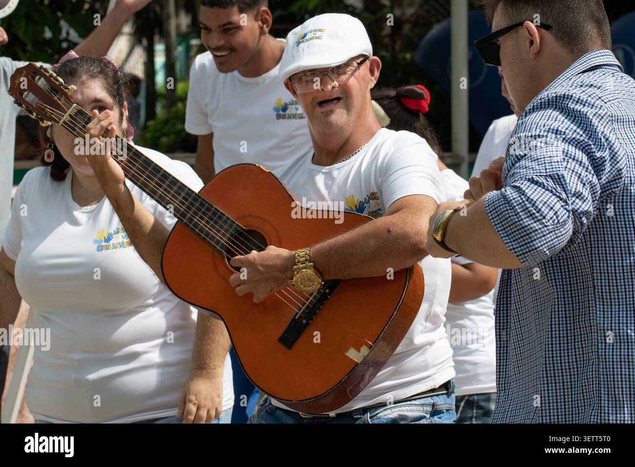 A young Cuban man with Down syndrome happily playing an acoustic guitar during a performance by the Unicos y Brillantes social project in Ciego de Avi Stock Photo