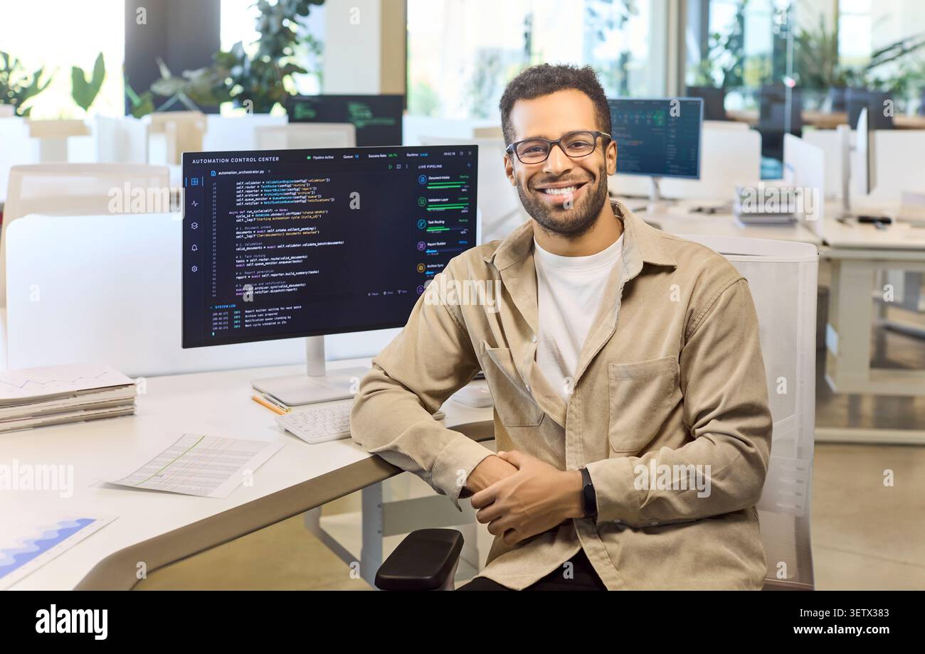 Confident software developer smiling at monitor with source code in bright office Stock Photo