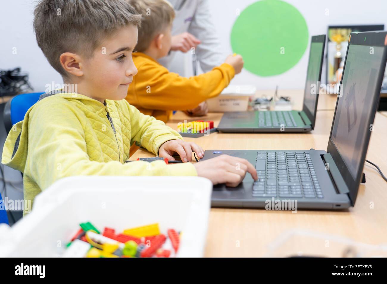 Student focusing on coding on a laptop in a classroom during a robotics workshop Stock Photo