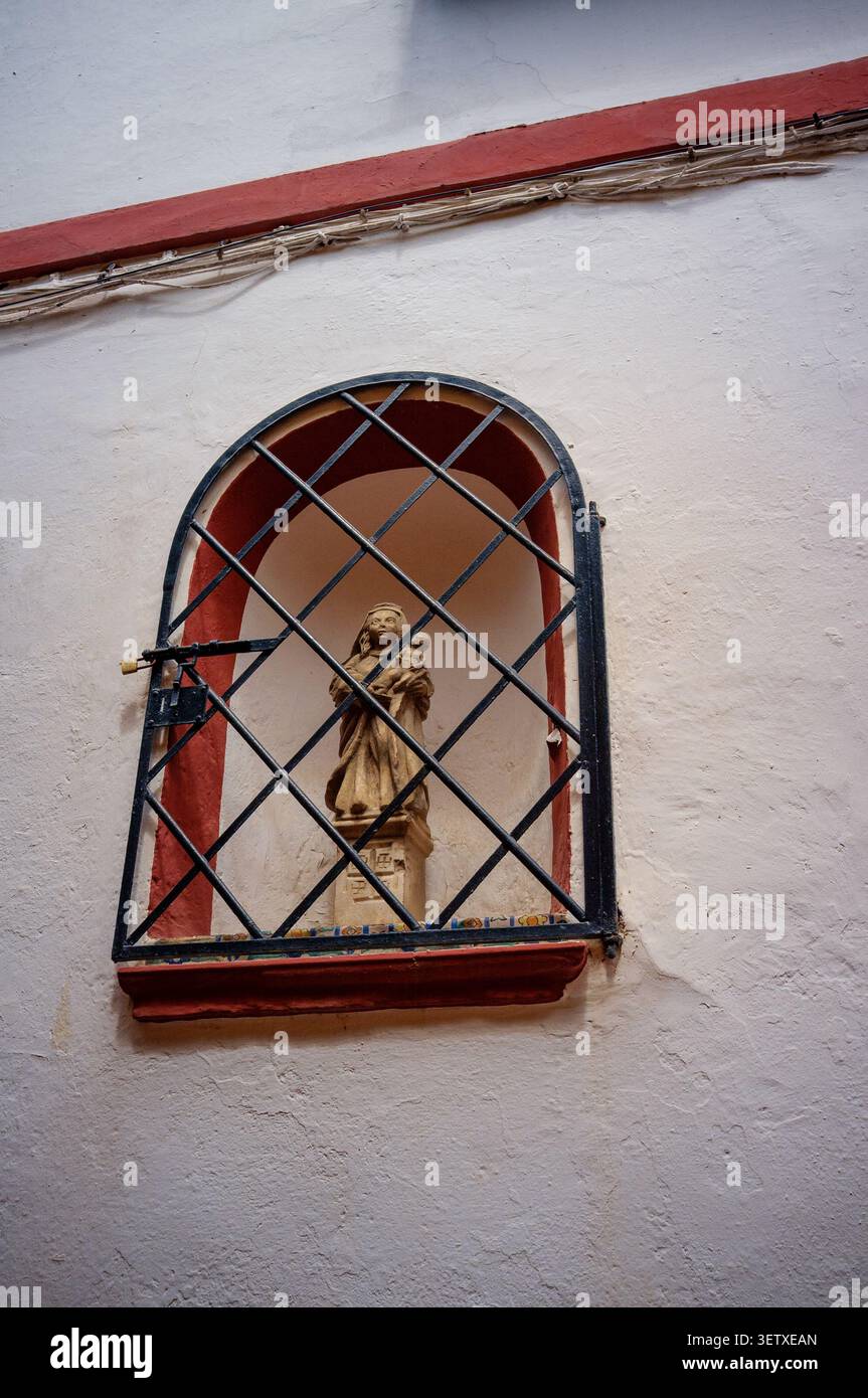 A street corner shrine with the statue of the Virgin Mary and Jesus covered with protective bars and padlock in Seville Santa Cruz area. Stock Photo
