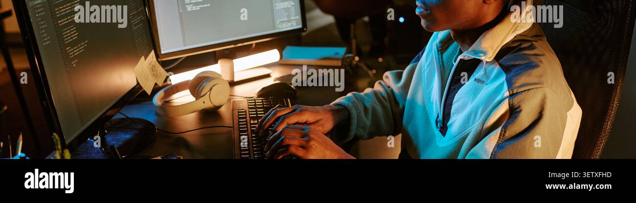 Header of Black Man Developing Software at Computer during Night Shift Stock Photo