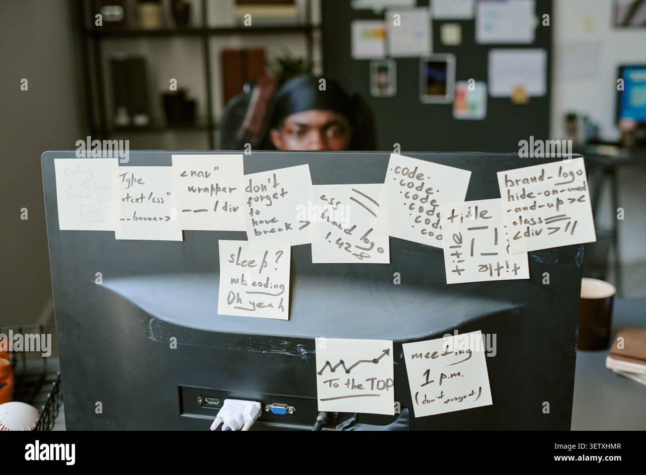 Adult Man Coding Behind Monitor Covered with Workflow Notes Stock Photo
