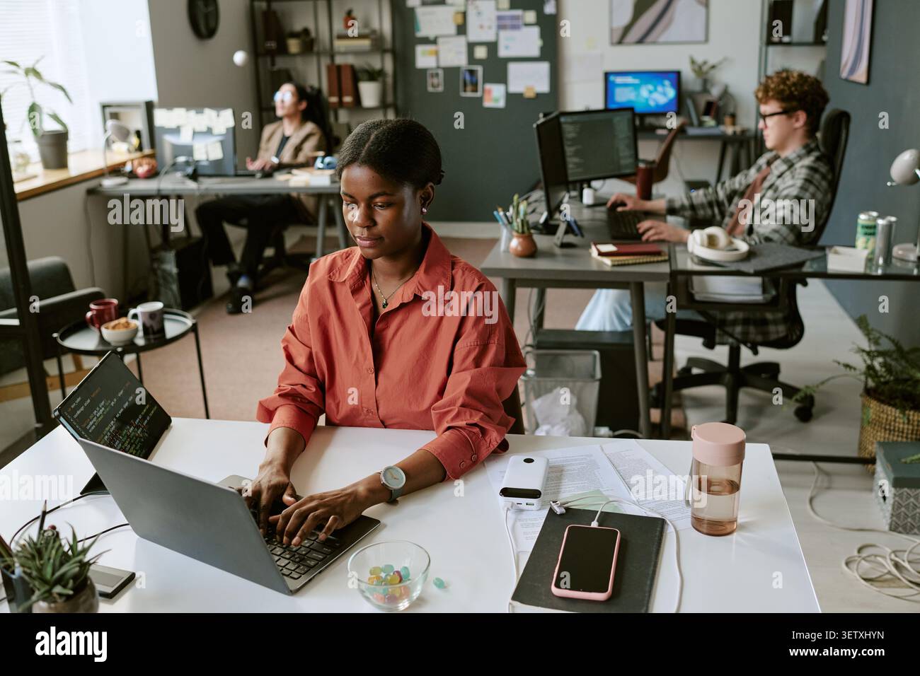 Black Woman Working on Laptop in Creative Office Team Setting Stock Photo