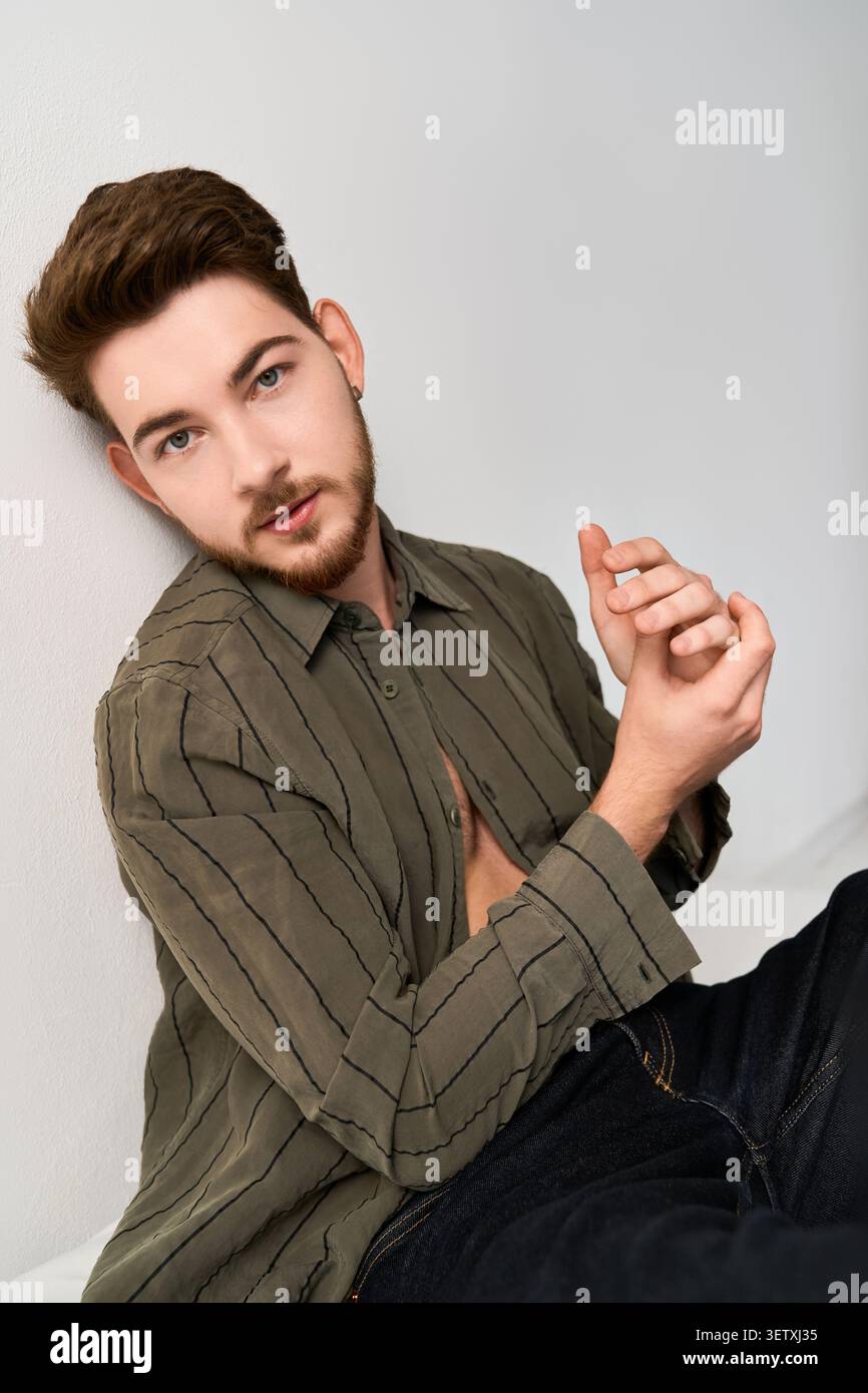 Charming young man with a beard poses effortlessly, highlighting modern casual style Stock Photo