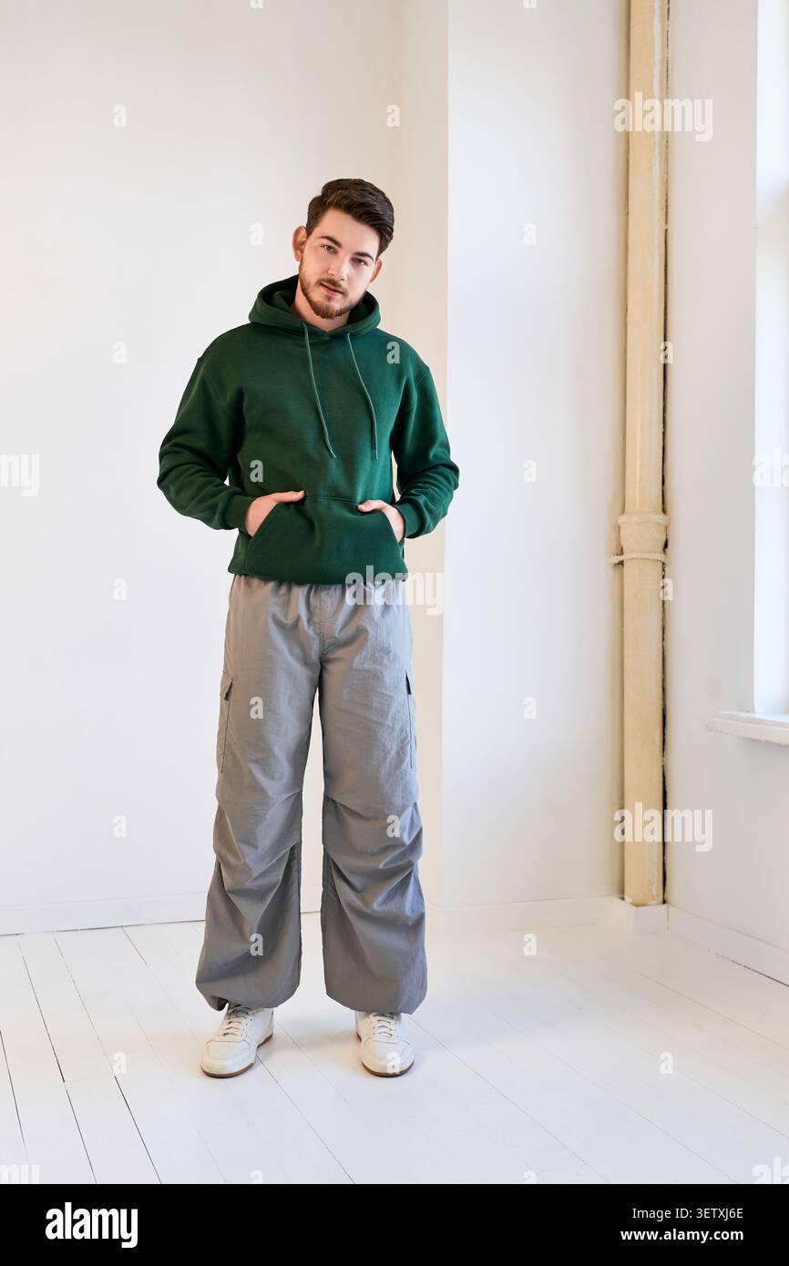 Confident young man with a beard poses in stylish casual wear in a bright studio Stock Photo