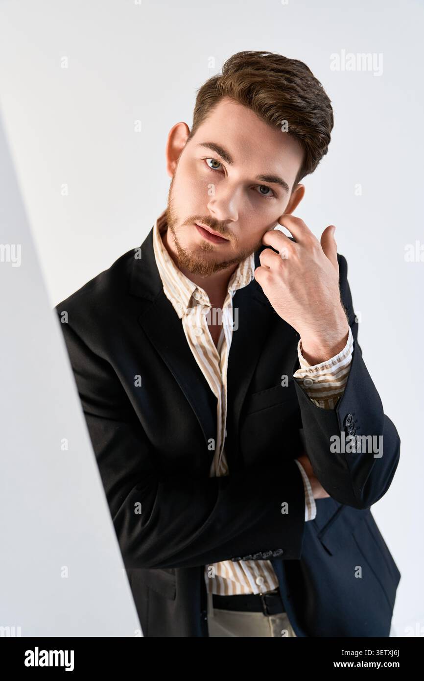 Young man with a beard poses confidently in a fashion-forward studio, embracing style Stock Photo