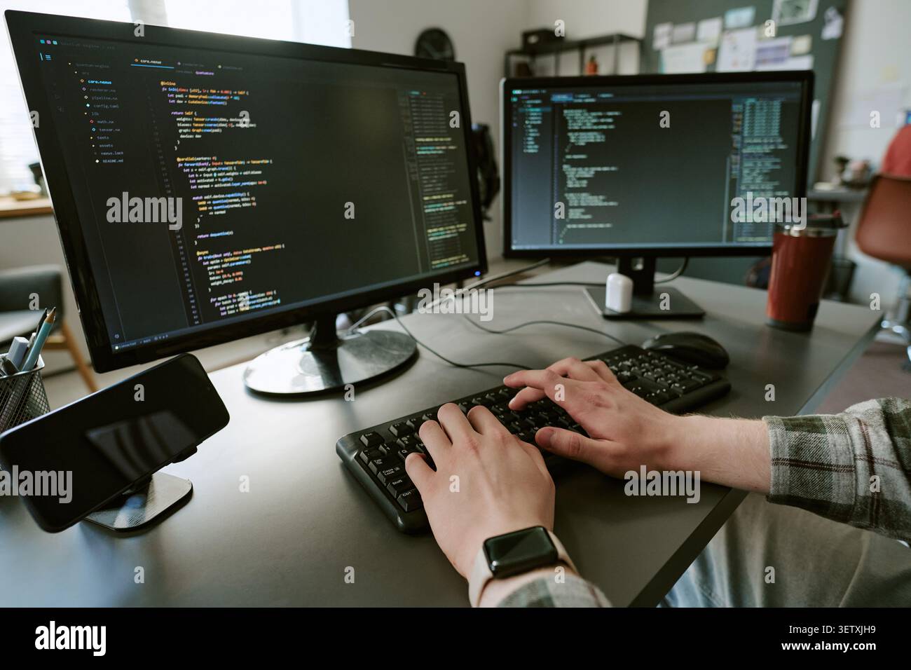 Adult Man Typing Code on Dual Monitors in Software Development Stock Photo