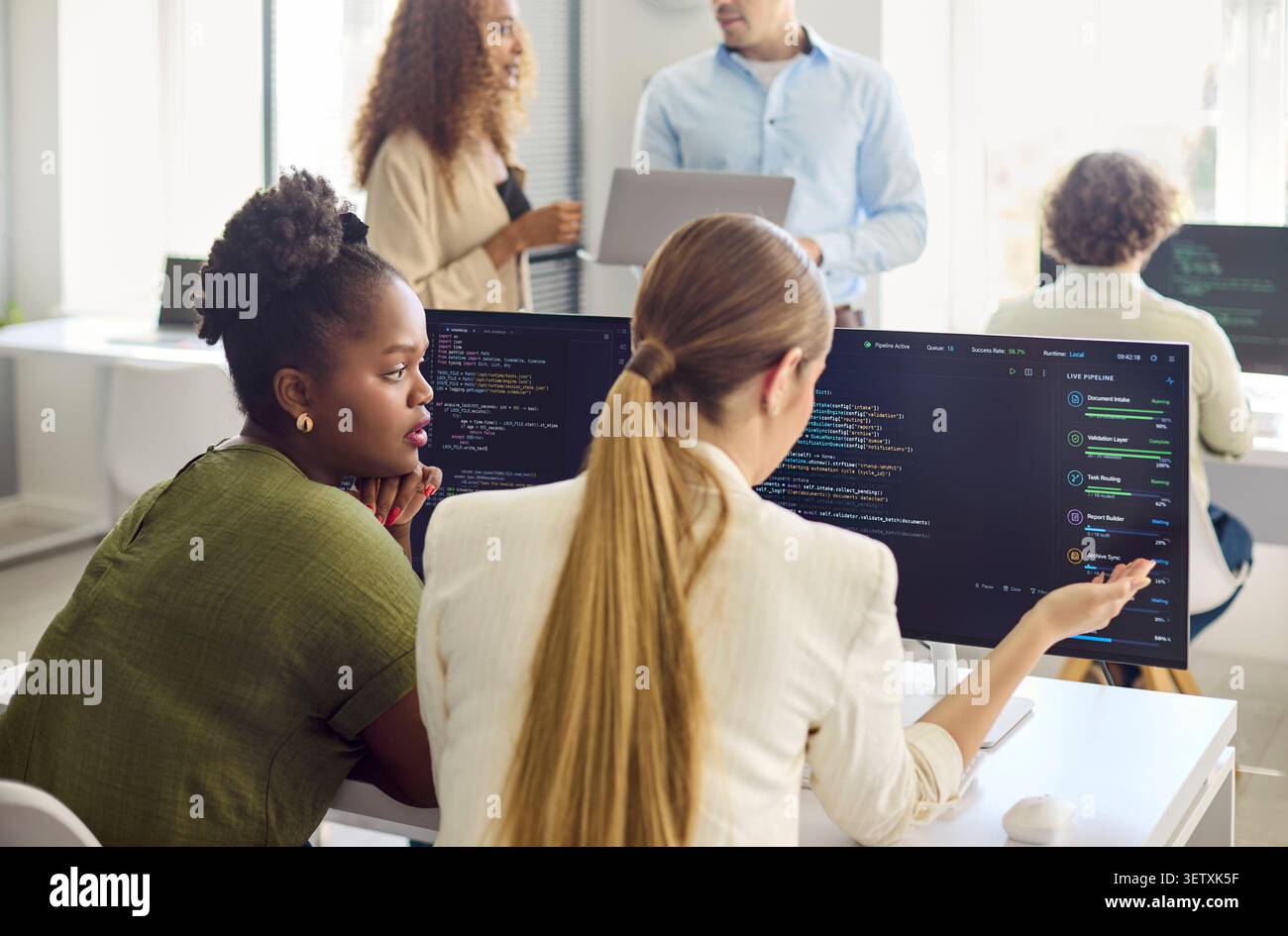 Developers collaborating on code review and mentoring in a modern tech office Stock Photo